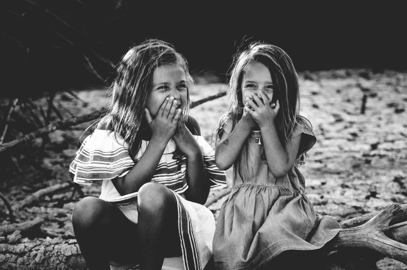 grayscale photography of two girls closing their mouths